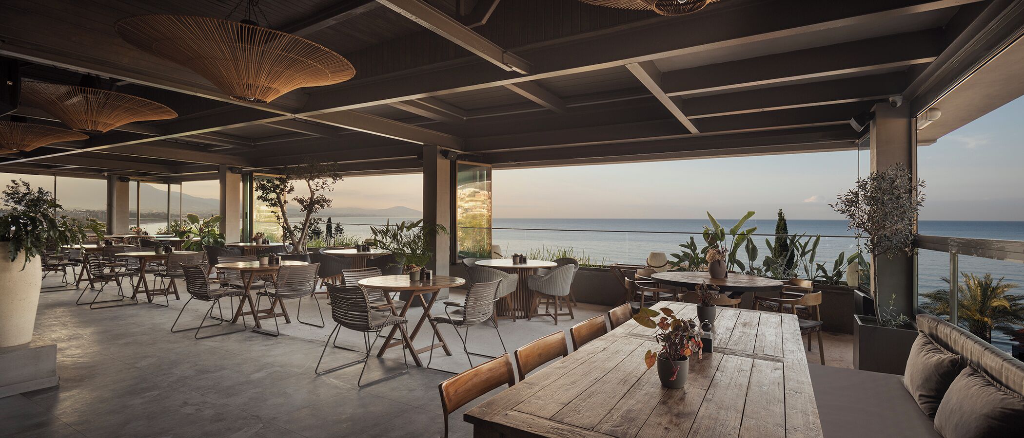 An outdoor seating area with tables and chairs, overlooking a body of water.