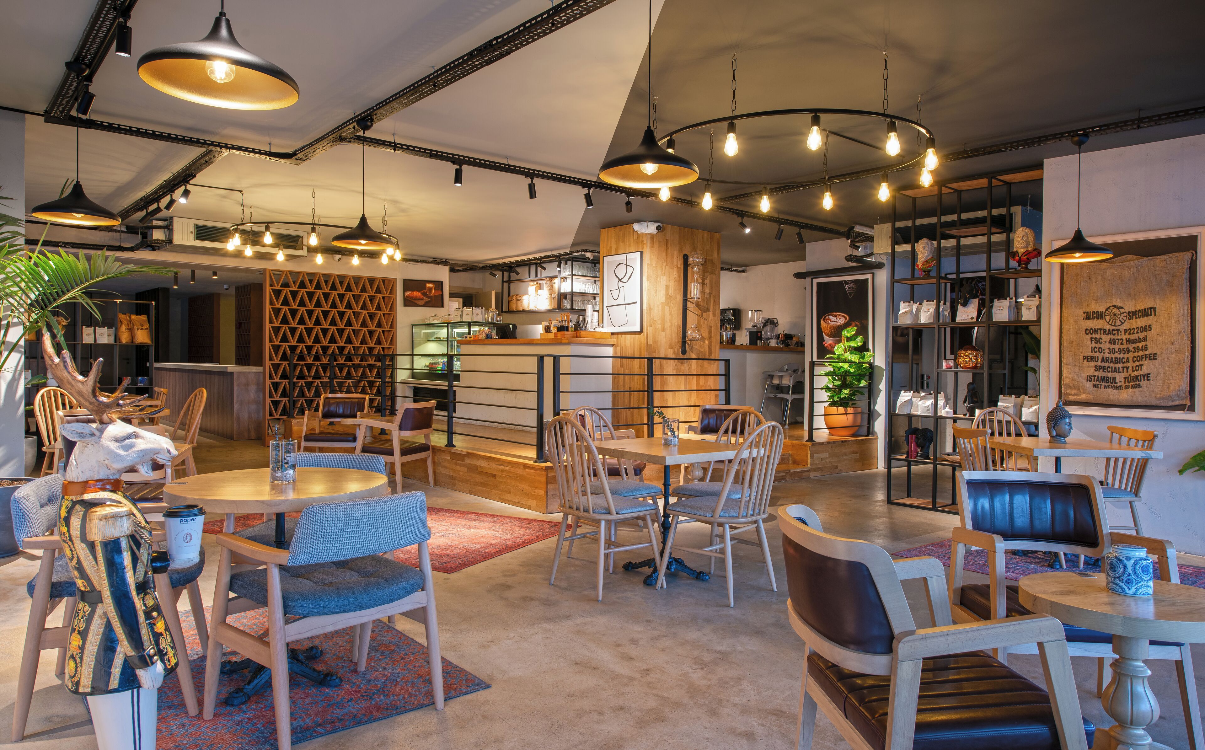 A cozy café with wooden furniture, pendant lighting, and a coffee bar.