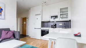 Een compacte keuken met witte kasten, een inbouwoven en een koffiezetapparaat.