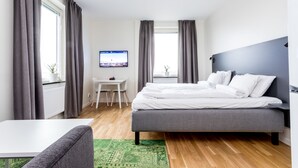 Een moderne slaapkamer met een bed, bureau en televisie.