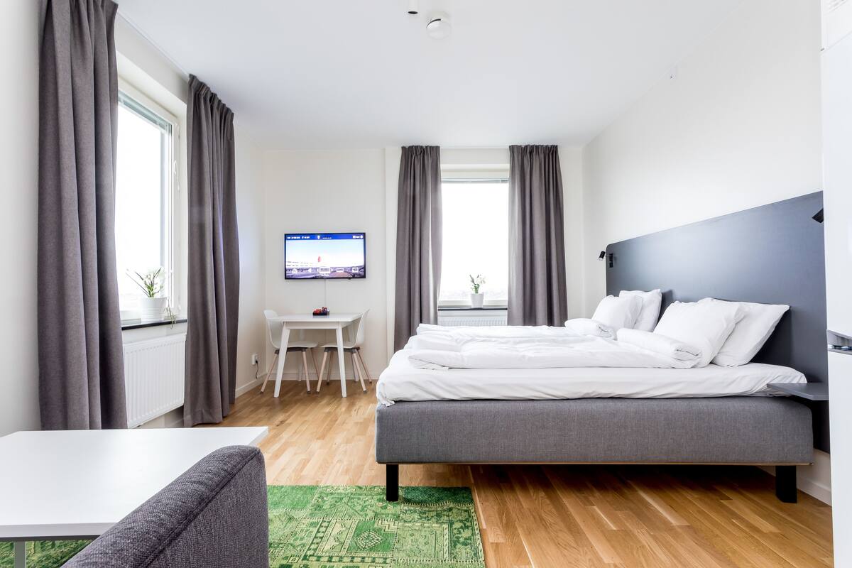 Un dormitorio moderno con una cama, un escritorio y un televisor.