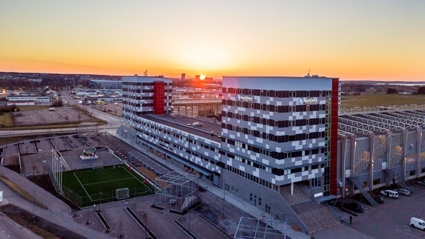 Een meerlaags gebouw met een modern architectonisch ontwerp, gekenmerkt door een opvallend rood verticaal element en een reeks balkons.