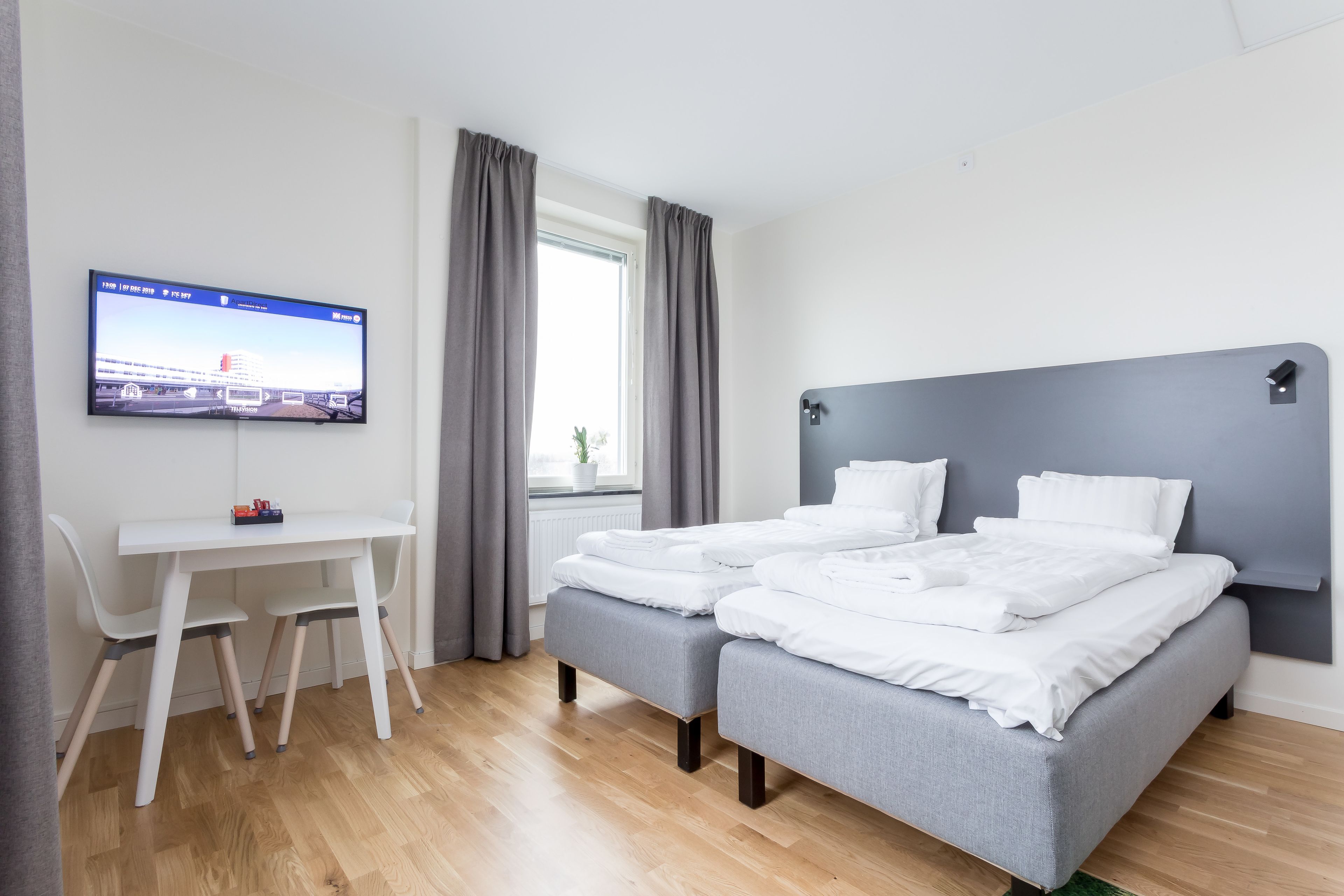 Ett modernt hotellrum med en säng, ett skrivbord och en TV.