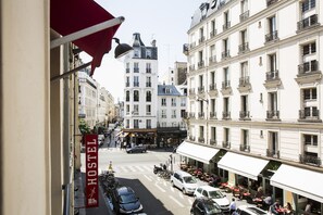 A street view with a hostel sign, parked cars, and buildings with balconies. - Auberge Internationale des Jeunes - Hostel (Paris)