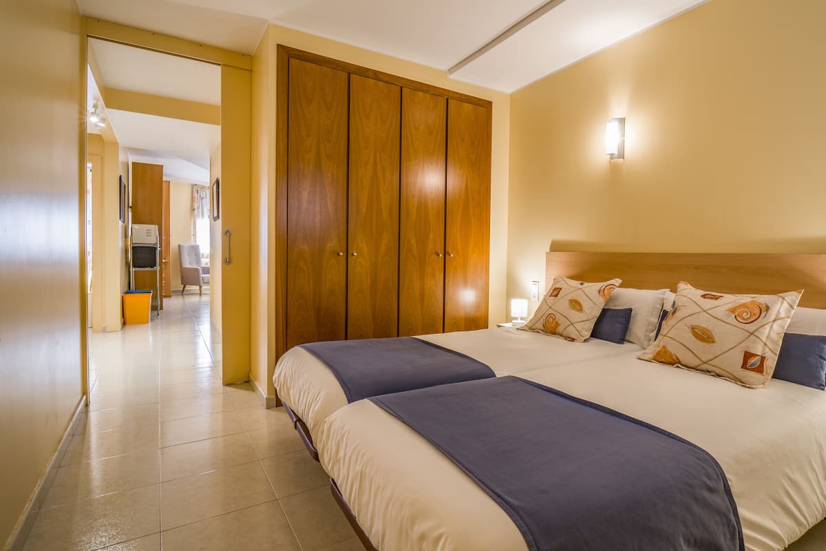 Une chambre d’hôtel avec un grand lit, une armoire en bois et un couloir menant à d’autres chambres.
