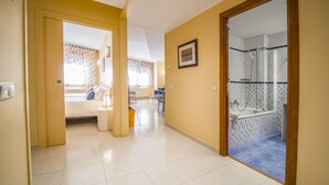 Un pasillo de hotel con una cama, un baño con ducha y un comedor.