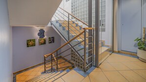 Una escalera moderna con barandillas de vidrio y pasamanos de madera que conduce a un segundo piso.