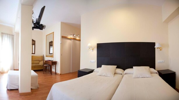 Una habitación de hotel con dos camas, un sofá, un escritorio y un espejo.