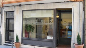 Entrada de un hotel con un amplio ventanal que muestra el nombre "HOTEL RUIZ".