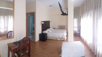 Een slaapkamer met een bed, een bureau, een stoel, een spiegel en een radiator.
