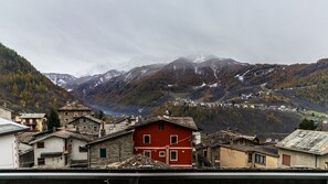 A mountainous village with traditional stone buildings, including a prominent red house. - Residence Pizzo Scalino (Chiesa in Valmalenco)