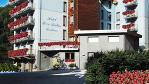 A hotel with balconies adorned with red flowers, a sign reading "Hotel Pizzo Scalino Residence," and a mountainous backdrop. - Residence Pizzo Scalino (Chiesa in Valmalenco)