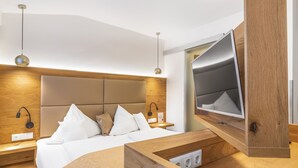 A modern hotel room with a wooden headboard, a flat-screen TV, a bedside table, and a built-in charging station. - Hotel Rösslwirt (Lam)