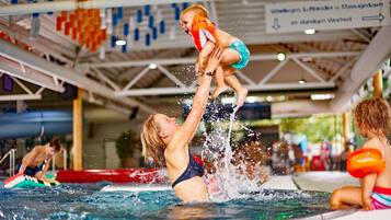Una piscina interior con una torre de salvavidas, un tobogán y un cartel que indica la zona de natación.