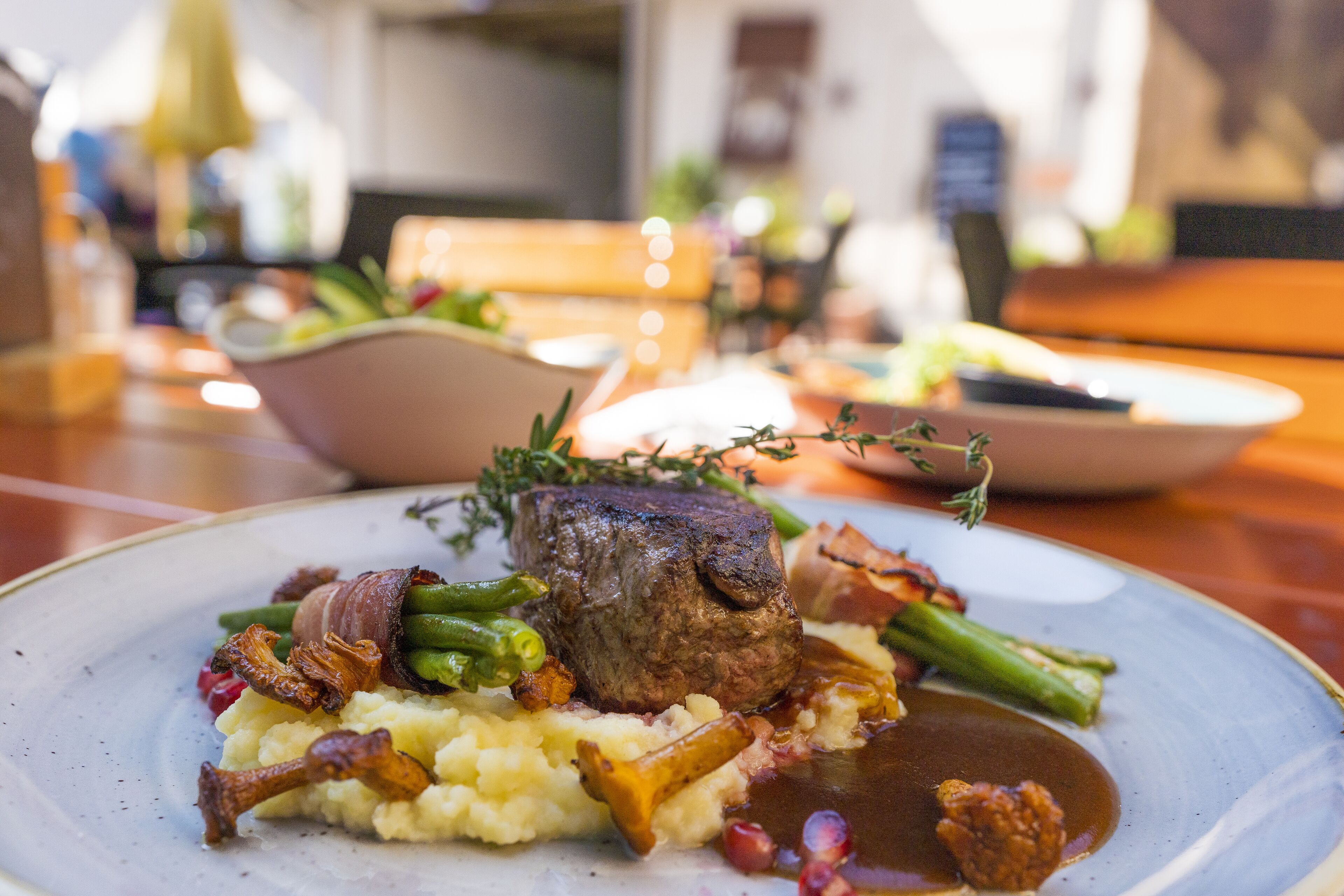 A plate of food with a steak, green beans, and mashed potatoes.
