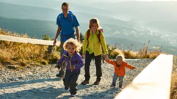 A family walking on a gravel path with a scenic mountain view in the background.