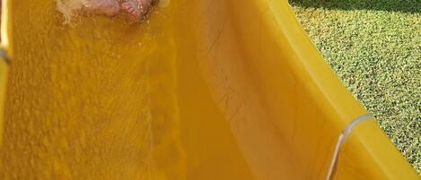 A person sliding down a yellow slide.
