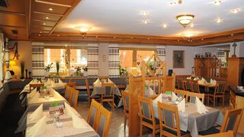Een restaurant met verschillende tafels en stoelen, een houten plafond en decoratieve verlichting.