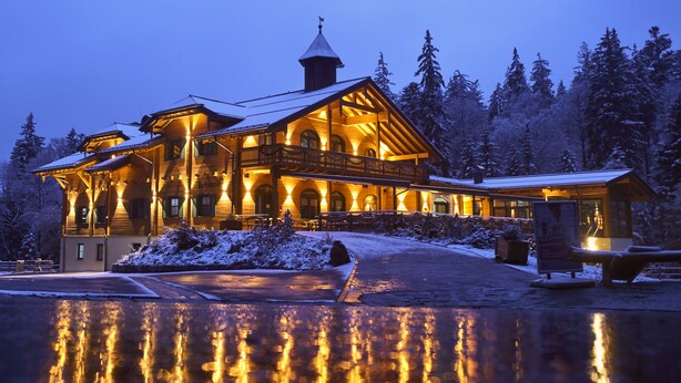A large, illuminated lodge with a prominent balcony and a snow-covered landscape. - Hotel Rösslwirt (Lam)