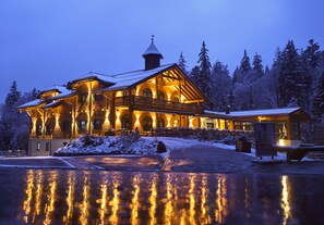 A large, illuminated lodge with a prominent balcony and a snow-covered landscape. - Hotel Rösslwirt (Lam)