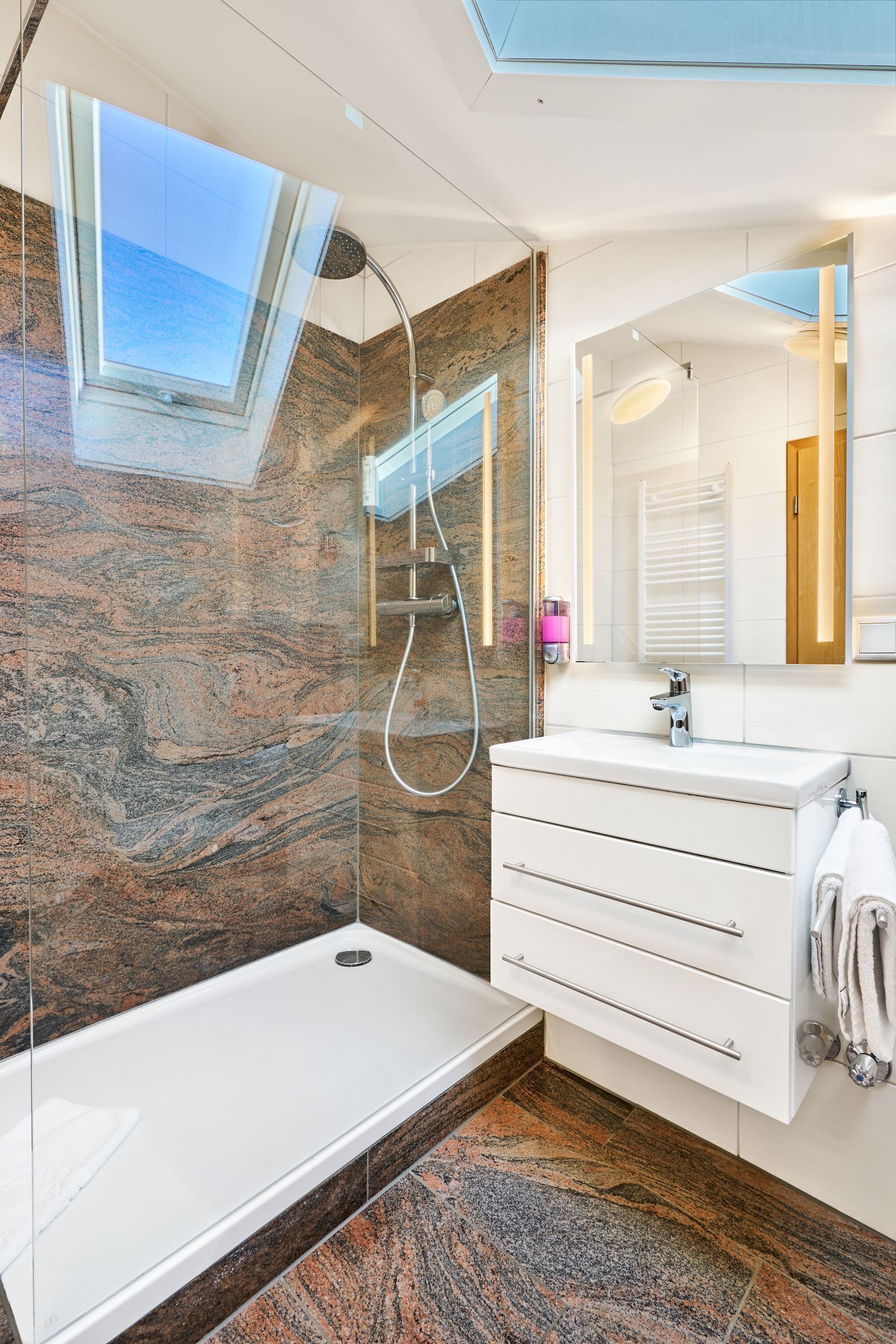 A modern bathroom with a glass-enclosed shower, a white vanity with drawers, and a large mirror.