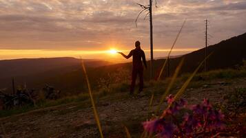Una persona in piedi su una collina con il sole al tramonto sullo sfondo.