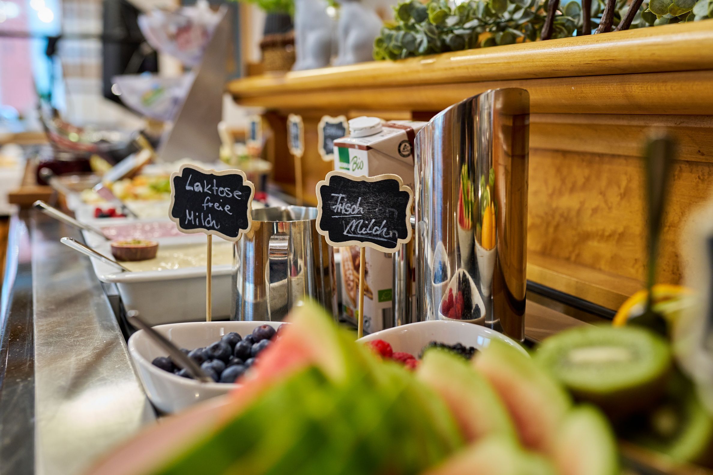 Ein Buffet mit beschrifteten Behältern für frische und laktosefreie Milch.