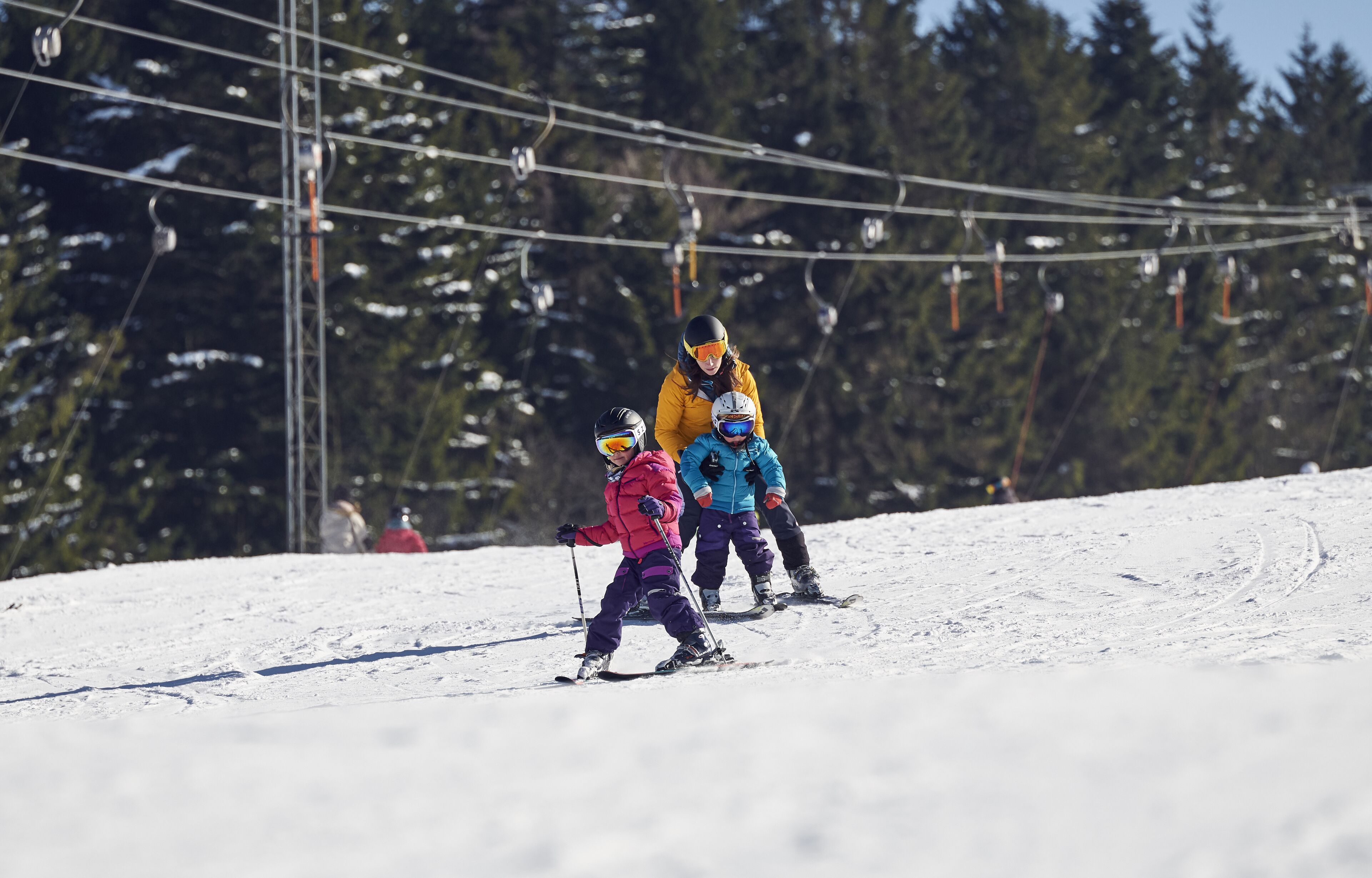 Une piste de ski avec des skieurs et un télésiège en arrière-plan.