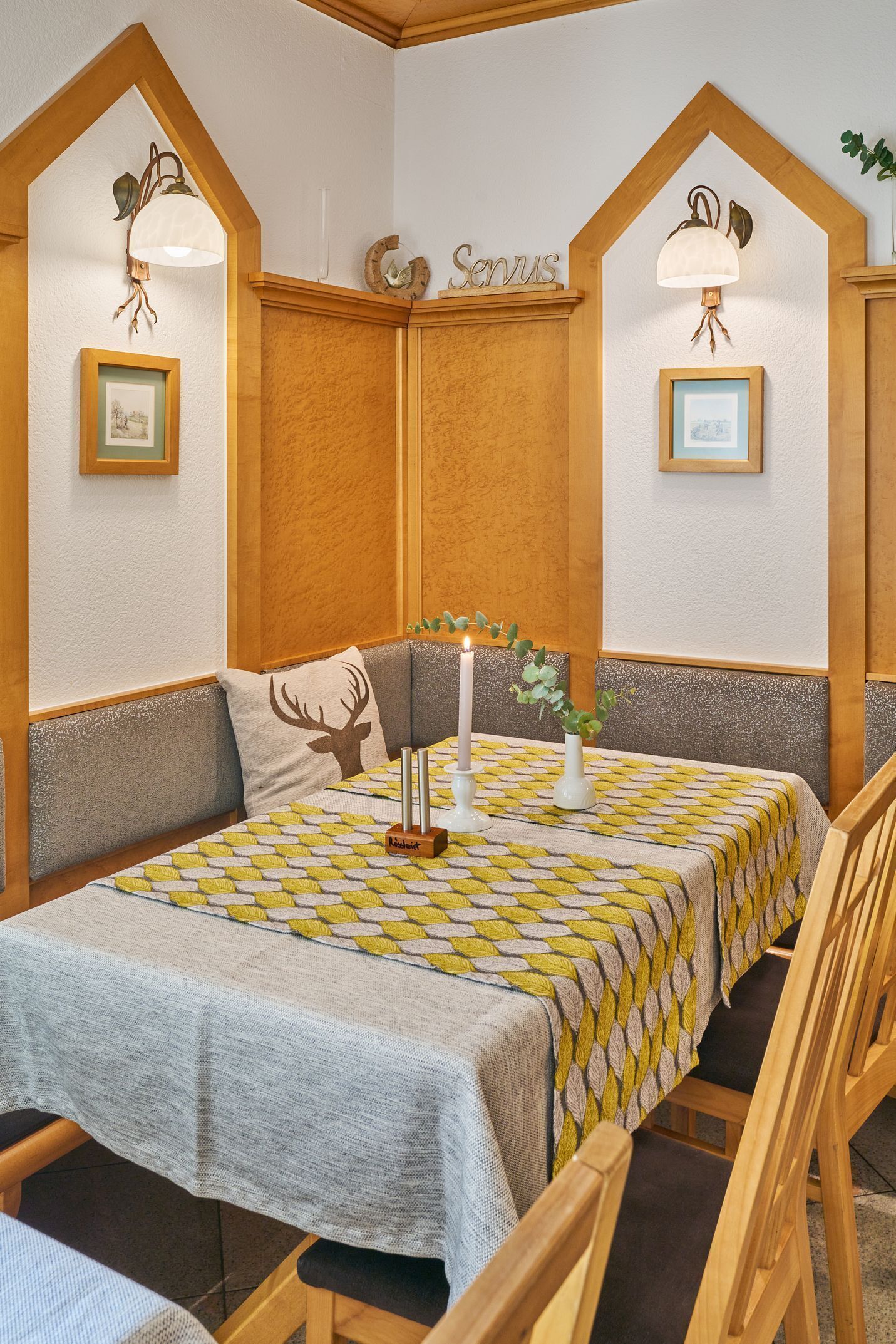 A cozy room with a bed, a table with a patterned tablecloth, and two wall-mounted lamps.