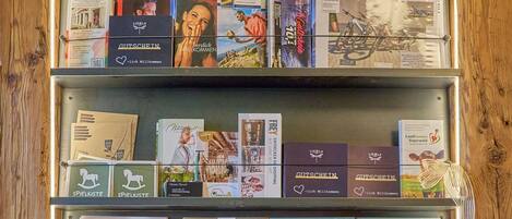 A wooden display case with books and magazines, a candle, and a decorative branch arrangement.