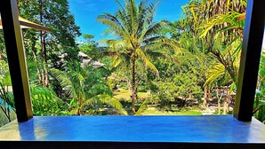 A balcony with two chairs and a view of a tropical garden with palm trees. - Flower Power Village (Ranong)