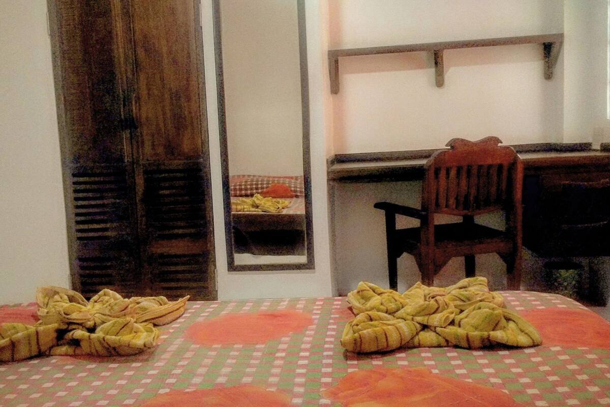 Una habitación con cama, una silla, un escritorio y un espejo.
