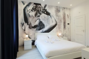 A bedroom with a large mural on the wall, a bed with white linens, two bedside tables with lamps, and a white door. - Suite Maggiore (Rome)