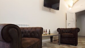 Una sala de estar con dos sofás de cuero marrón, una mesa de centro y un televisor de pantalla plana montado en la pared.