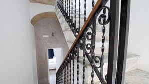Una escalera con barandilla de hierro forjado negro y suelo de mármol.