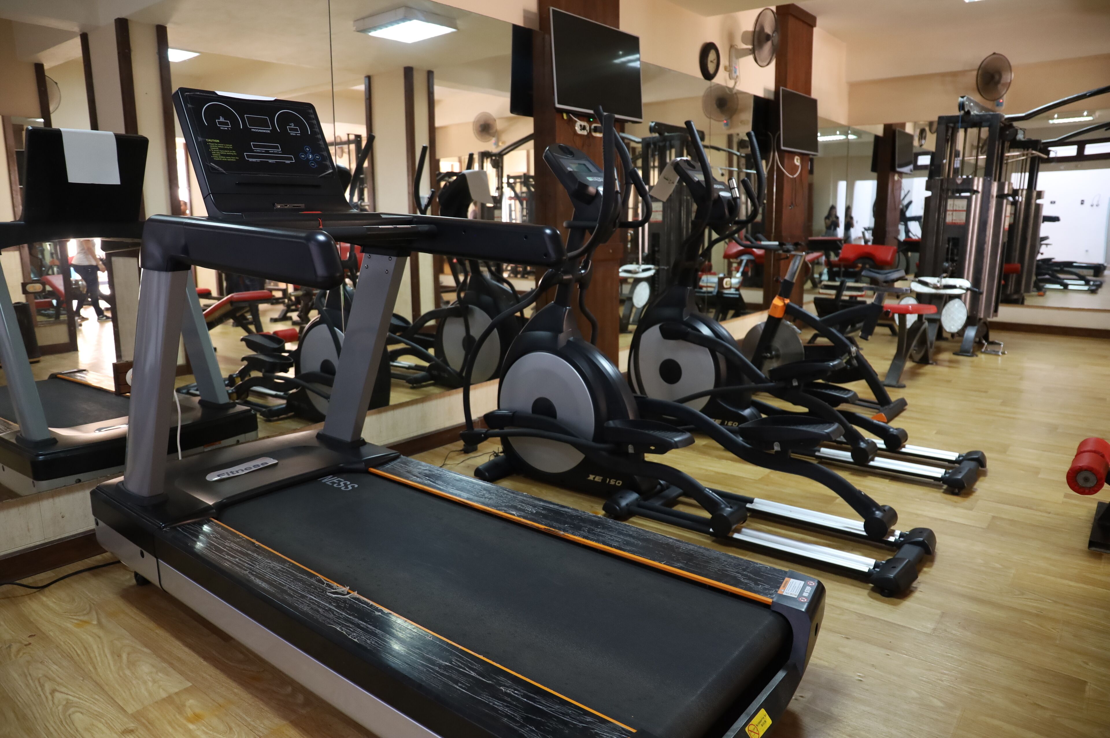 A gym with various exercise equipment including treadmills, stationary bikes, and weight machines.