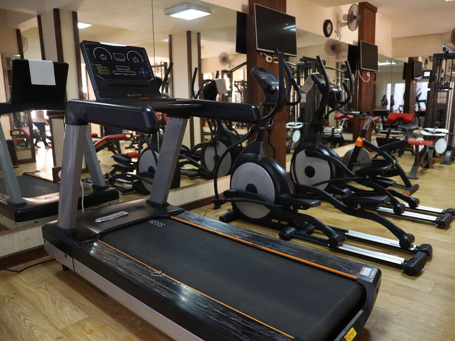 A gym with various exercise equipment including treadmills, stationary bikes, and weight machines.