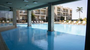 Una piscina al aire libre, sombrillas, sillones reclinables de piscina