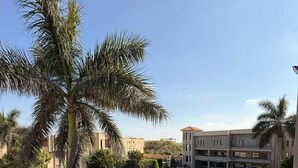 A view of a hotel with a swimming pool, a well-maintained lawn, and palm trees. - Panacea Suites Hotel (Borg el Arab)