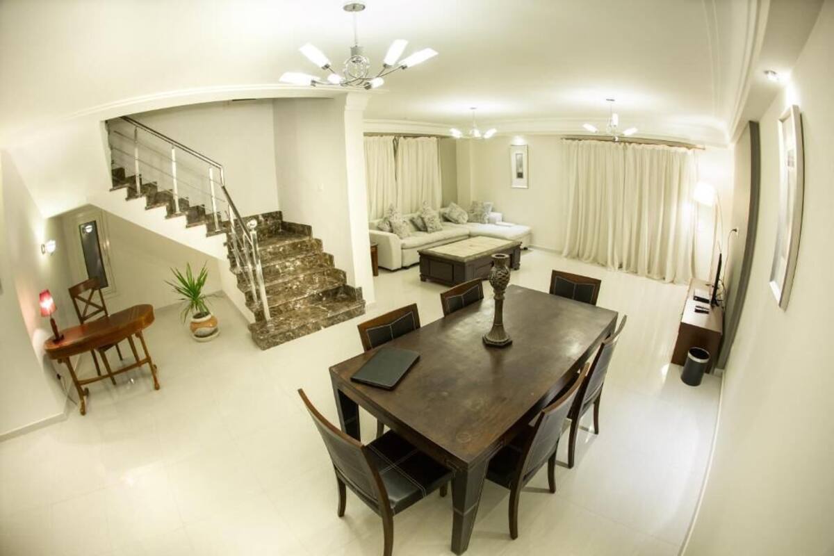 A spacious living area with a dining table, sofa, and staircase.