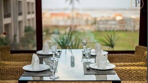 A dining table set for four with a view of a cityscape through a window. - Panacea Suites Hotel (Borg el Arab)