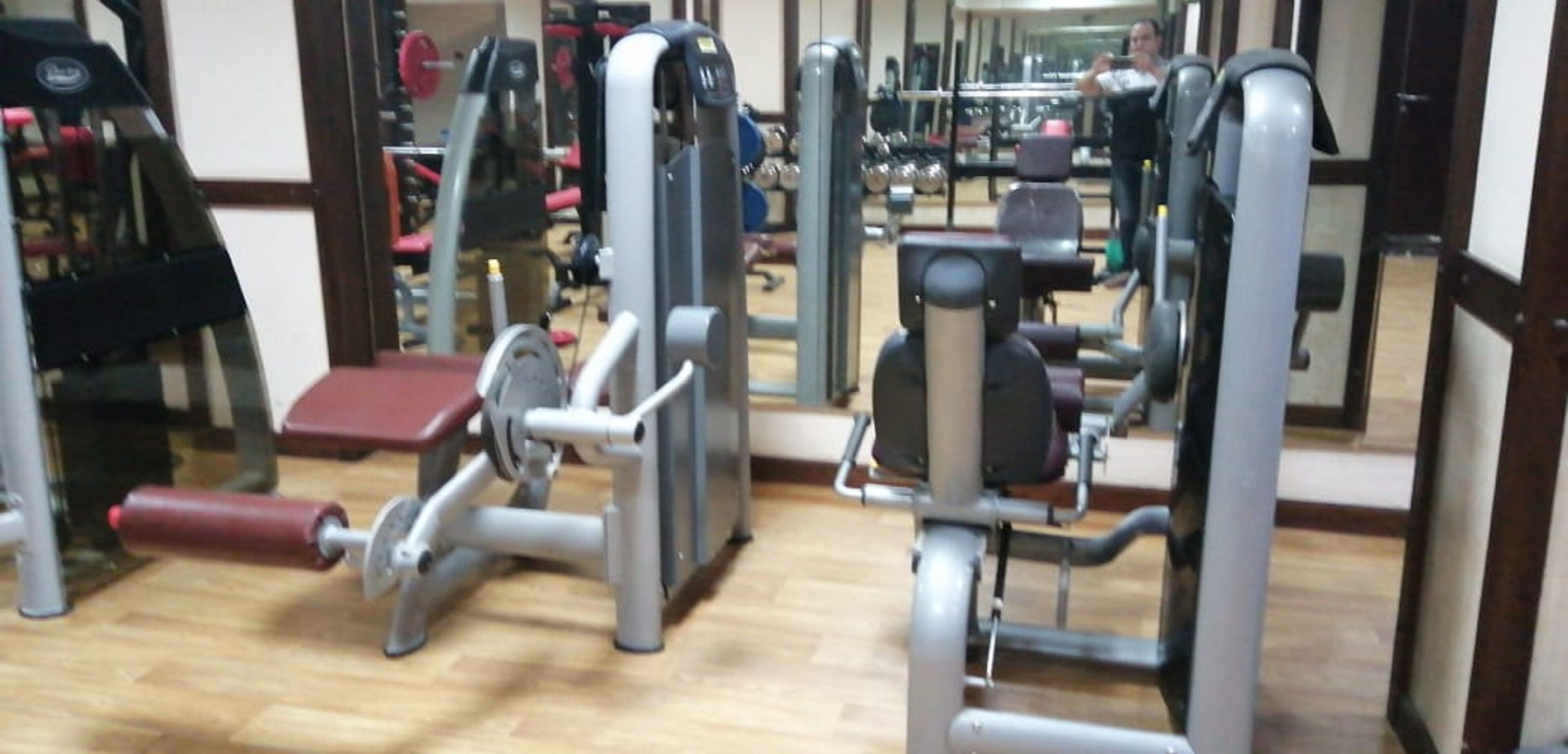 Et fitnessrum med forskellige træningsmaskiner, heriblandt en benpres og en brystpres.