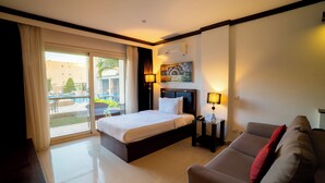A hotel room with a bed, a sofa, a desk, and a view of the outdoors. - Panacea Suites Hotel (Borg el Arab)