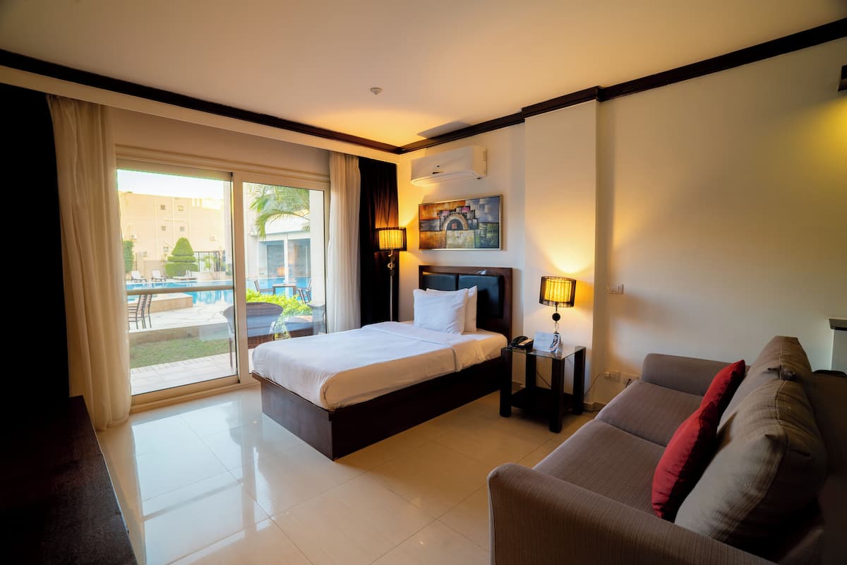 A hotel room with a bed, a sofa, a desk, and a view of the outdoors.