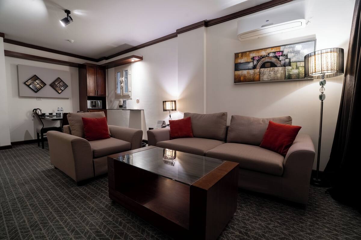 A modern living room with a sofa set, a coffee table, and a dining area with a table and chairs.