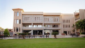 A multi-story hotel with a central courtyard, outdoor seating, and a pool area. - Panacea Suites Hotel (Borg el Arab)