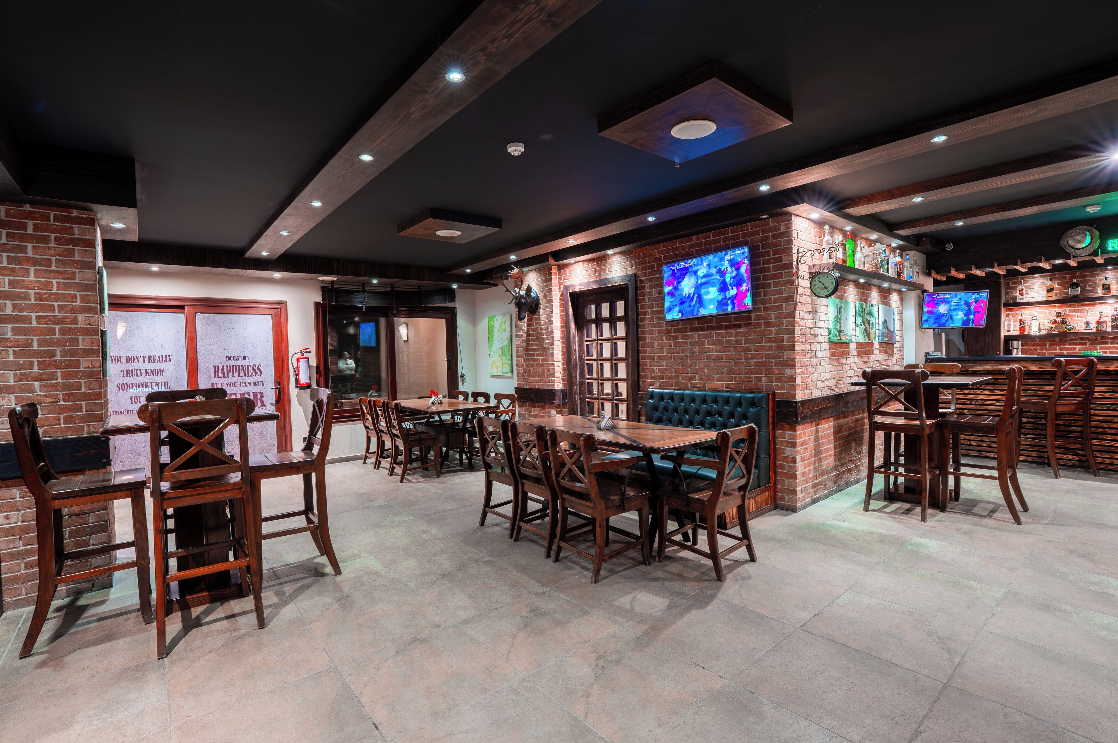 A restaurant with brick walls, wooden tables and chairs, and multiple screens displaying content.