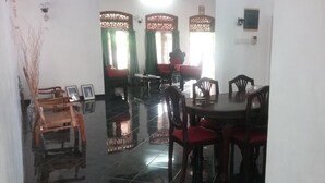 A dining area with a round table, chairs, and a wooden chair in the corner. - Villa Relax (Galle)