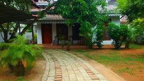 A paved pathway leading to a building with a tiled roof and a porch area. - Villa Relax (Galle)