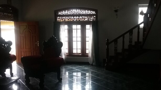 A dimly lit room with a tiled floor, a wooden bench, and a window with curtains. - Villa Relax (Galle)